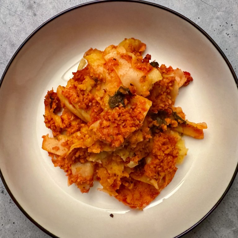 Plat de lasagne avec sauce tomate et garniture, servi dans une assiette blanche.
